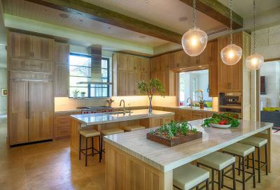 Twin-island white oak kitchen with cypress beams and seeded glass pendants